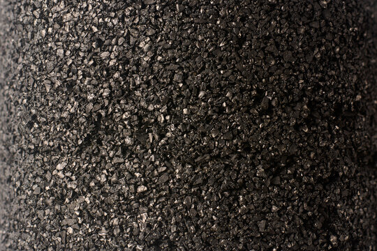 black granular activated carbon filter in full frame background, cylindrical water purification cartridge in close-up view, industrial plumbing component