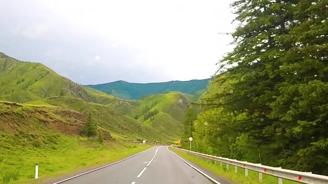 Driving along a winding mountain road through green hills and forest. Scenic road trip. Countryside travel and adventure. Alpine landscape and nature