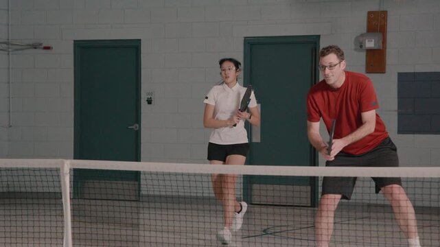 Co ed pickleball players in a modern gymnasium
