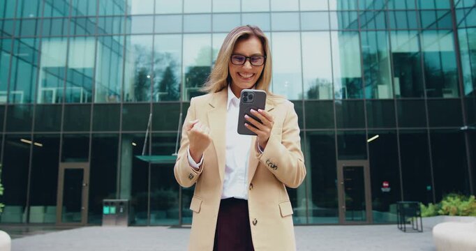 Close up of amazed woman holds digital tablet reading good news, happy to receive notification, gestures actively from happiness, outdoors. Emotions and pleasant feelings concept