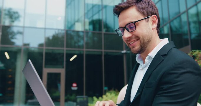 Portrait of handsome man copywriter using laptop computer, typing, working freelance project online, outdoors