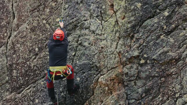Inspiring slow motion of a beginner's first solo rock climbing ascent. Capturing the raw tension, focus of a novice mastering a steep vertical cliff. Ideal for educational and sports content..