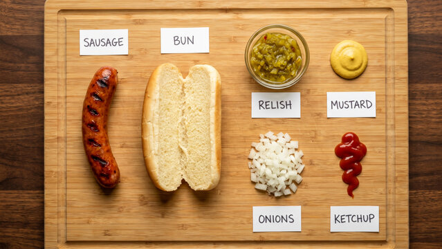 hot dog ingredients organized with handwritten labels on a wooden board
