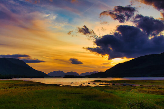 Stunning golden sunset over Loch Leven with mountains of Glen Coe in the background, Scottish Highlands.