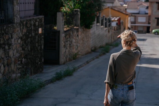 Blonde Woman Walking Along Quiet Residential Street in Summer