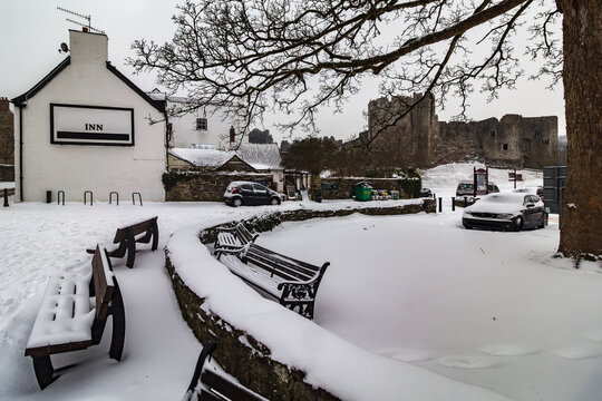 Traditional inn covered in winter snow with historic Chepstow Castle visible in the background in Chepstow