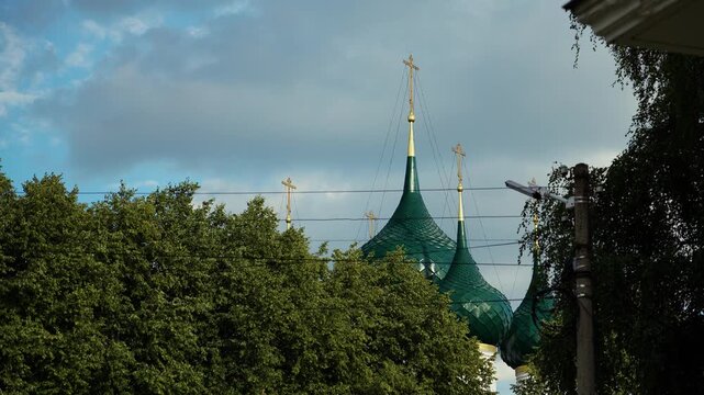 Green tented church domes with golden crosses rising above trees in Yaroslavl city