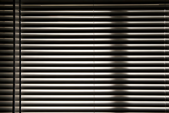 Blinds in black and white, when closed, form repeating lines, soft gradients, and shadow patterns to achieve a minimalist look, a privacy concept, an architectural element, or an abstract background