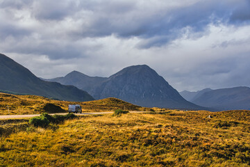 An off-road vehicle driving on a scenic road with Buachaille Etive Mor mountain in the background, Glen Coe, Scotland. © Tomasz German