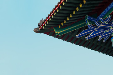 A fragment of traditional Chinese architecture is a decorative roof cornice with elements of douxiong coupling and bright blue—green-red painting © Shauerman