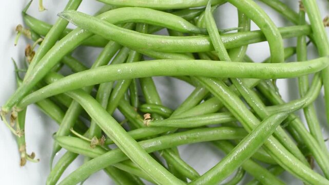 Italian green beans from the Lazio region on a white plate,extreme close-up, rotating video.