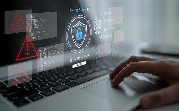 A person interacts with a laptop displaying cyber security graphics, highlighting alerts and threats. This image emphasizes the importance of online safety in a digital world. Ledger