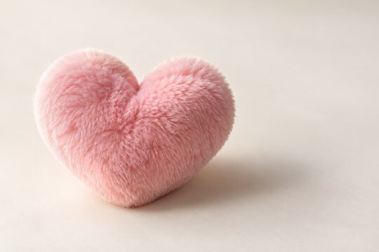 Single soft pink heart with delicate texture on a clean pale romantic background