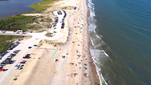  Parked vehicles recede beside a Chincoteague area beach bordered by breaking waves.
