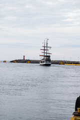 Pirate Ship Sailing into the Sea with a Lighthouse on the Coast © GoldenCarry 