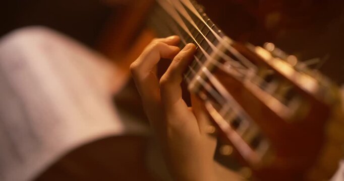 Cinematic extreme close-up of a musician playing classical guitar with dynamic camera movement, warm amber lighting, shallow depth of field, motion blur, and an intimate musical atmosphere