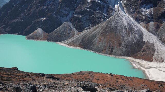 Stunning turquoise glacial lake surrounded by rugged, snow dusted mountains in himalayas of nepal. Showcasing serene and remote beauty of the high altitude alpine landscape