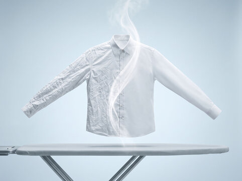 Crisp white dress shirt transforming from wrinkled to perfectly pressed and smooth with magical steaming effect hovering directly above a modern metal ironing board inside minimalist studio setting