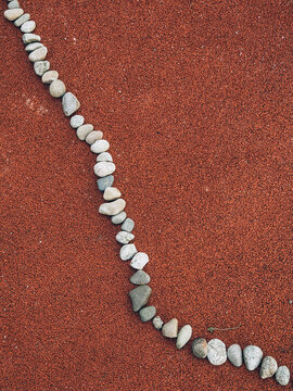 Sinuous line of gray stones on red textured background minimalist composition