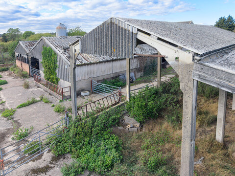 Drone view of a now derelict dairy farm in Essex, UK. Showing the asbestos roof and overgrown hay storage areas. In the distance would have been the milking parlour.