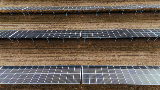 Aerial view of a solar farm with rows of photovoltaic panels installed on open ground in Utrine, Vojvodina, Serbia.