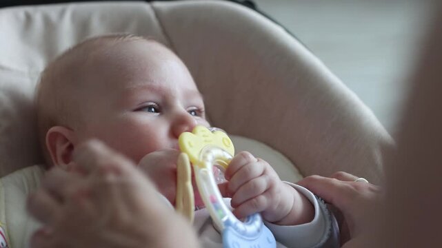 Mother giving a teething toy to her newborn baby