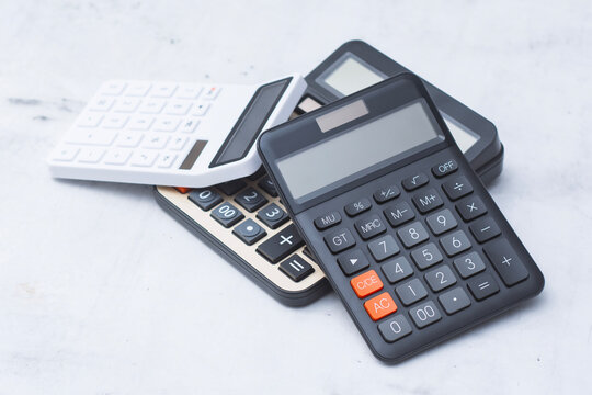 Stack of black and white electronic calculators lying on light background. Accounting calculation, financial audit, tax report budget, office bookkeeping and business analysis concept.