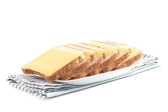 Slices of whole wheat toast bread with cheddar cheese on white plate and striped napkin isolated on white background. Healthy breakfast, dairy food, quick snack and meal staging concept.