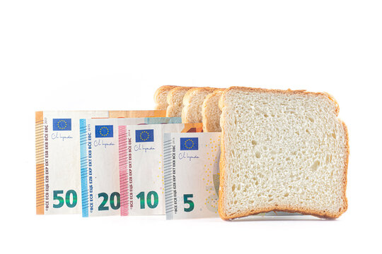 Sliced white toast bread standing in row with euro banknotes on white background. Food price inflation, cost of living crisis, grocery expenditure and financial inflation impact concept.