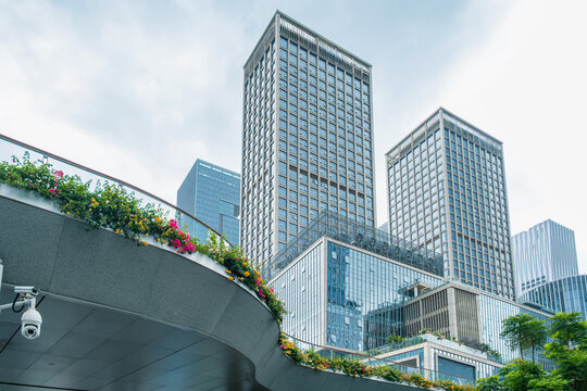 Modern glass office buildings with landscaped terraces and flowering greenery in Shenzhen, China. Contemporary business architecture, urban development, green city planning