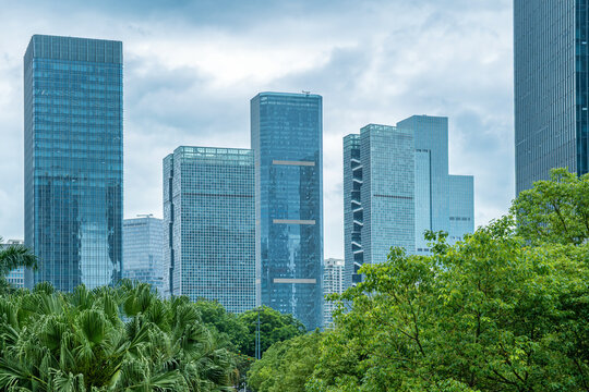 Modern glass office buildings with tropical trees and urban greenery in Shenzhen, China. Green city development, sustainable architecture, modern business environment and ecological metropolitan