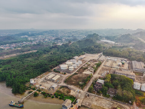 Aerial view of Pro Tank Terminal fuel storage facility with large industrial tanks, pipelines, and a jetty on the riverbank in Samarinda, East Kalimantan, Indonesia.