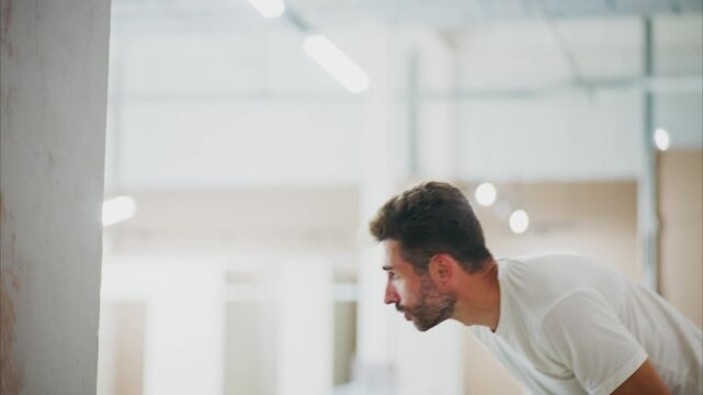 Man stretches arms upward, mid-movement. Focus on his side profile, focused expression. Bright, airy room, clean, simple background. Ideal for fitness, wellness, or daily routine concepts