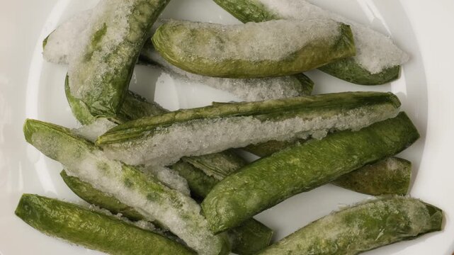 White plate with frozen cut green beans rotating