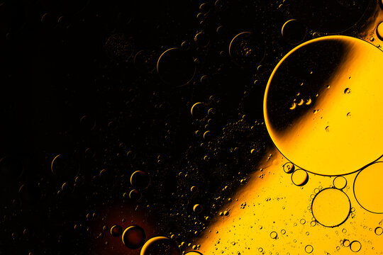 Bright golden oil bubbles floating in dark liquid mixture