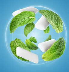 Menthol chewing gum pieces and mint leaves in air against blue background © New Africa