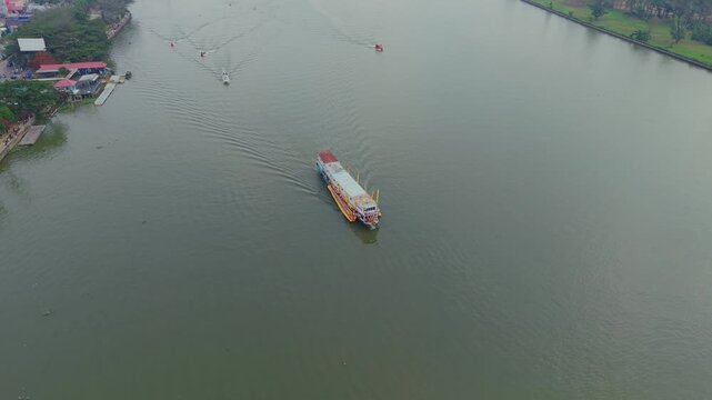 Tenggarong, Indonesia - 27 September 2026: Aerial view of the Ngulur Naga Erau ceremonial boat navigating the Mahakam River with smaller escort vessels.