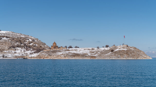 Akdamar Island in Lake Van, Turkey, in winter, with the Armenian Church of the Holy Cross on its snowy shore and a Turkish flag on the hilltop