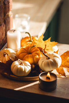 Aesthetics, seasonal atmospheric vibes. Thanksgiving dinner decor idea. Cozy home decoration on the windowsill with little pumpkins and candles. Aromatherapy for fall season.