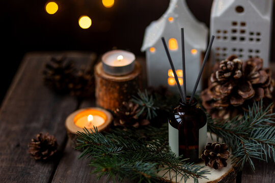 Aroma burning candles, aromatic reed diffuser in glass bottle. Cozy Christmas atmosphere at home. Holiday scent, aromatherapy. Fir tree fragrance, spruce, cedar, winter mood, knitted sweater