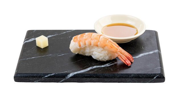 Isolated delicious cooked shrimp sushi nigiri ebi on a dark marble board with dipping sauce.