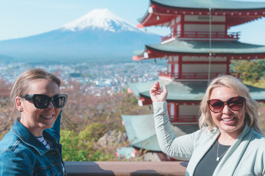 Two women travelers pose at Chureito pagoda, Mt Fuji mountain viewpoint in Shimoyoshida, Japan. Enjoying view