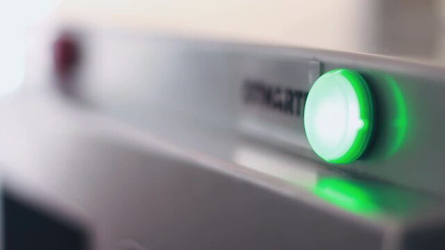 Green start button illuminates machine close up. Rack focus red indicator lamp.