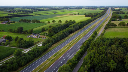 Aerial highway cars on road from above in countryside landscape with meadow farmland fields and nature forest. Horizontal drone photo infrastructure theme.  © Laura