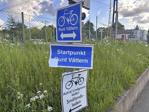 Signpost with cycle path signs on blooming meadow under partly cloudy sky, cycle races around Lake V&auml;ttern, Lake V&auml;ttern, J&ouml;nk&ouml;pings l&auml;n, Sweden
