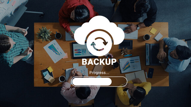 A team collaborates in a stylish office, focusing on cloud backup and progress. Laptops, charts, and documents illustrate modern business solutions and innovative approaches. Ledger