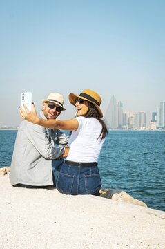 Couple, bonding and phone taking selfie in Doha city on travel vacation date or social media memory. Smile, happy man and woman on mobile photography technology explore middle east. Doha, Qatar