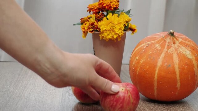 Autumn Thanksgiving arrangement, still-life background. Harvested pumpkins, a beautiful bouquet of yellow and orange flowers, fruits and vegetables, autumn leaves, and red berries on a wooden table. A