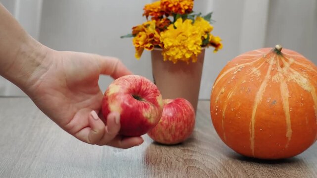 Autumn Thanksgiving arrangement, still-life background. Harvested pumpkins, a beautiful bouquet of yellow and orange flowers, fruits and vegetables, autumn leaves, and red berries on a wooden table. A