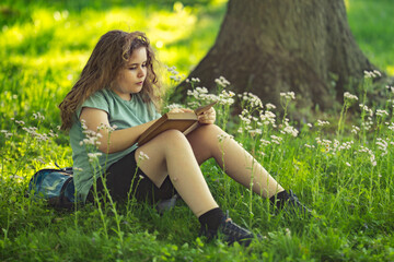 Fototapeta premium Smart kid studies storybook outdoors. Focused smart reader builds knowledge. Smart childhood connects education and nature. Smart learning feels creative and calm.